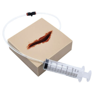 Square training pad moulded with an open laceration, fitted with clear tubing and a syringe that feeds simulated blood to the wound