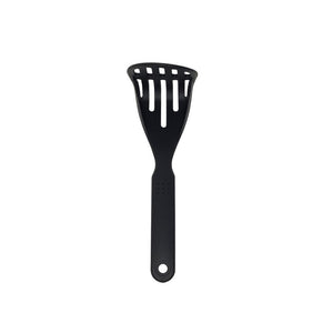 Connoisseur black potato masher standing upright on white, showing the flared head cut with long slots and the slim handle with a hanging hole