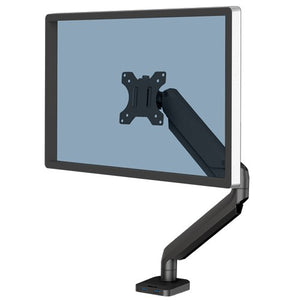 Fellowes Platinum Series single monitor arm in black holding a screen, with the base plate and USB ports visible on the desk