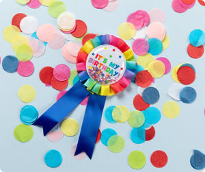 Rainbow Giggle and Grow birthday badge with a happy birthday message and multicoloured metallic confetti visible inside the clear front pocket.
