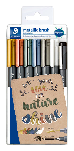 Staedtler metallic brush and pigment liner hangsell box showing six metallic brush pens in gold, red, green, blue, grey and white plus a black liner, above hand lettered words on kraft card