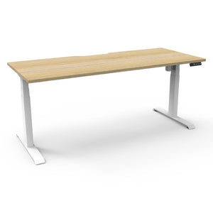Rapidline Boost Light single sided electric sit-stand desk with a natural oak top on a white frame, with the controller at the front right edge