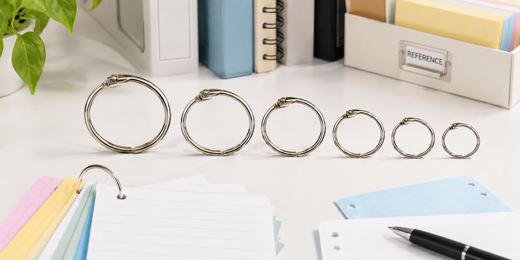 Assorted metal book and binder rings arranged with index cards on a bright white office desk.
