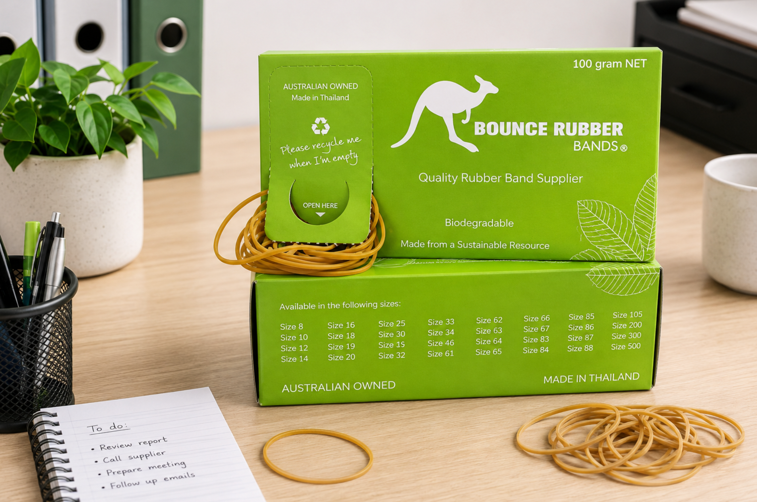 Bounce 100g rubber bands and dispenser on a bright office desk with stationery and filing supplies.