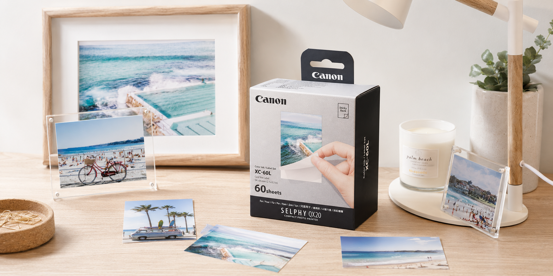 Canon Selphy compact photo paper displayed on a bright timber desk with printed photos and acrylic frames.