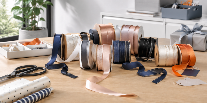 Premium gift wrapping workspace with assorted craft ribbons, scissors, tags and neatly styled wrapping supplies.