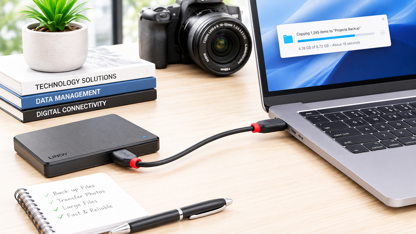 Data transfer cable connected between a laptop and external drive on a bright modern workspace desk.