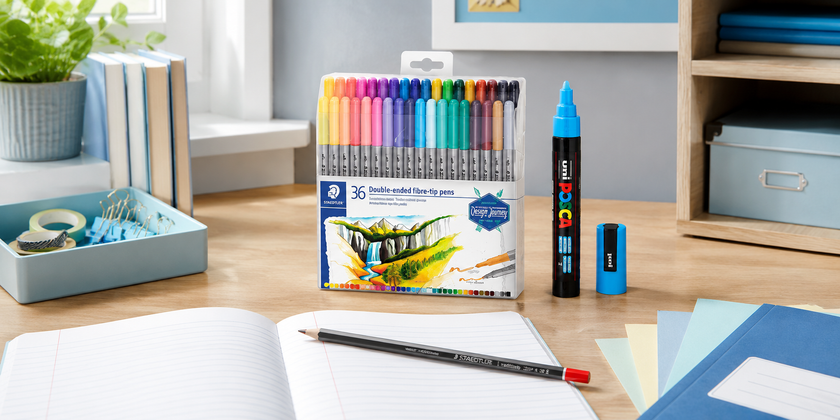 Colourful education writing supplies on a classroom desk with open notebook, pencil, paper, organiser tray and school stationery