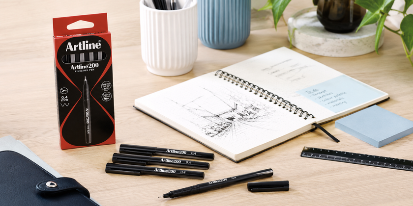 Artline fineliner pens and pen pack on a clean design desk with open sketchbook, ruler, sticky notes and planning accessories