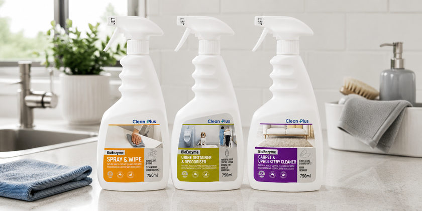 All-purpose cleaner spray bottles on a bright kitchen bench with cleaning cloths, sink and washroom accessories in the background.