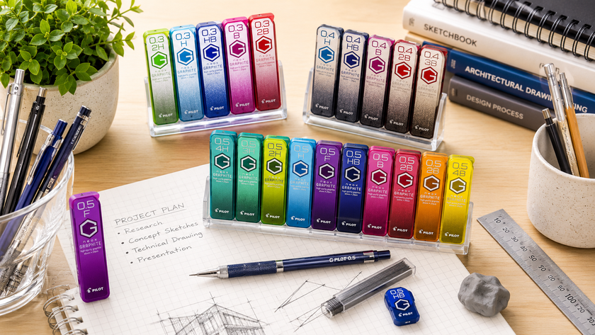Mechanical pencil lead refills arranged on a bright drafting desk with pacer pencils, graph paper, ruler and technical sketches.