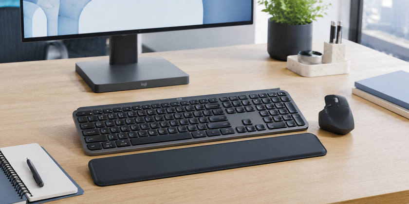 Keyboard and mouse combo arranged on a modern office desk with monitor, wrist rest, notebook and tidy workspace accessories.