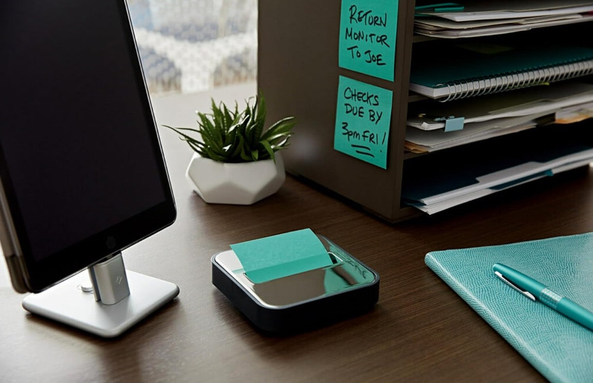 Pop up sticky note dispenser on an office desk with quick access notes beside a monitor and stationery.