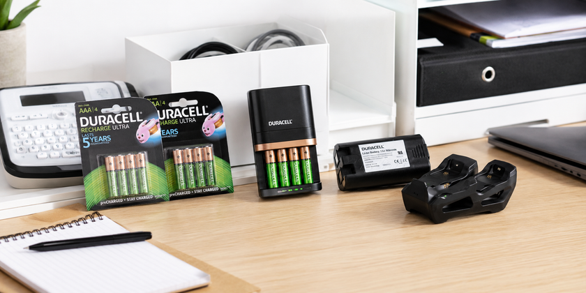 Rechargeable battery packs, chargers and device batteries arranged on a clean office tech desk with stationery and storage accessories.