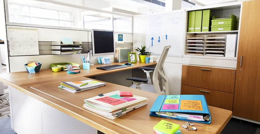 Sticky notes used across an office workstation with binders, documents and folders for reminders and planning.