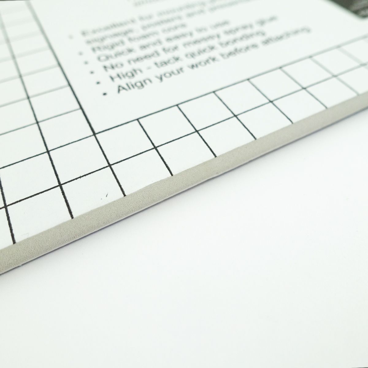 Close view of a Quill Self Adhesive Foam Board edge, showing the 5mm foam core under the gridded top sheet and printed instructions