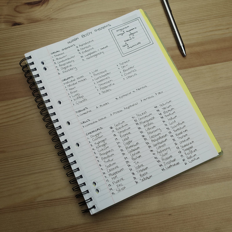 Quill Q Series 3 subject book open to a ruled page of handwritten notes, beside a pen