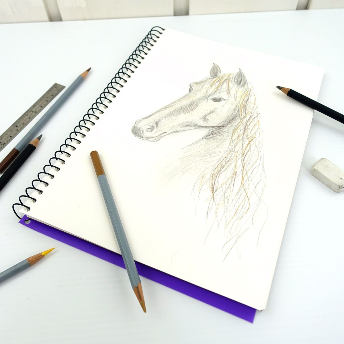 Quill Visual Art Diary A4 open to a pencil drawing of a horse on the white cartridge page, with pencils, a ruler and an eraser on the desk