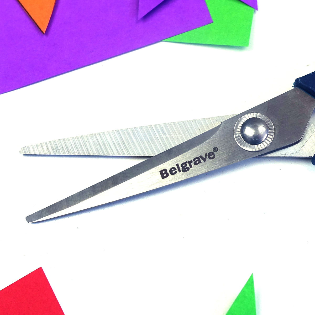 Close-up of Belgrave SC1 stainless steel blades marked Belgrave, over sheets of coloured paper