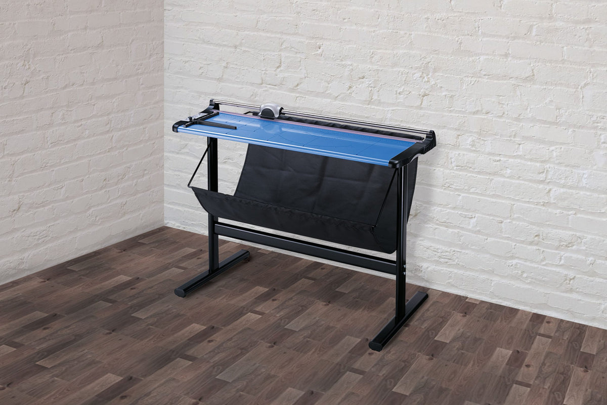 Ledah 960 trimmer on its black steel stand with the fabric cuttings tray, against a white brick wall