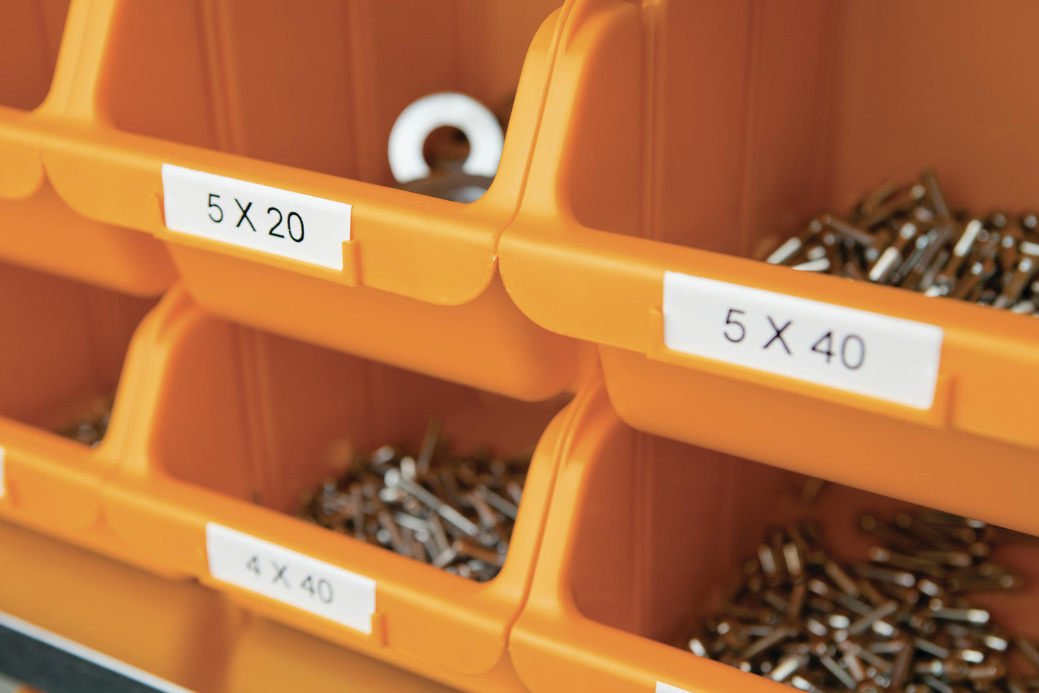 Orange storage bins with labeled compartments containing screws.
