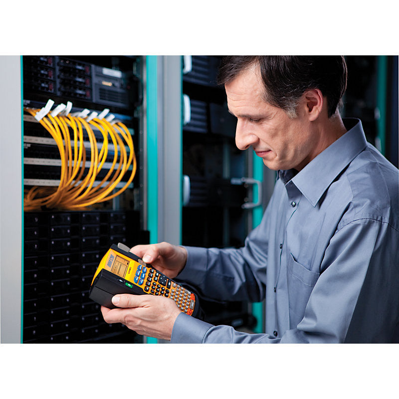 Man using a label printer in a server room with network cables.