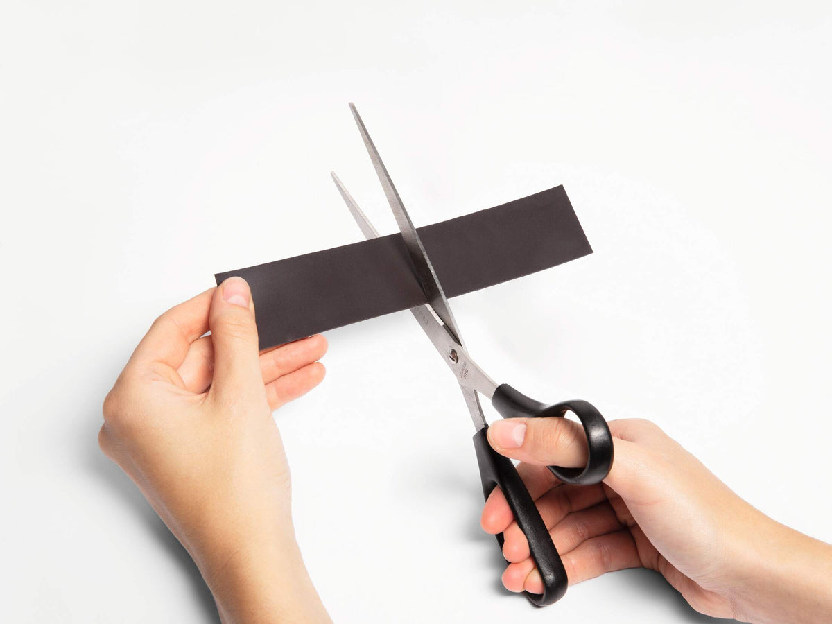 Hands cutting a length of Durable magnetic tape with scissors