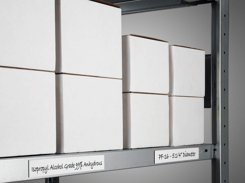 Handwritten white magnetic tape labels along a grey steel shelf with boxes
