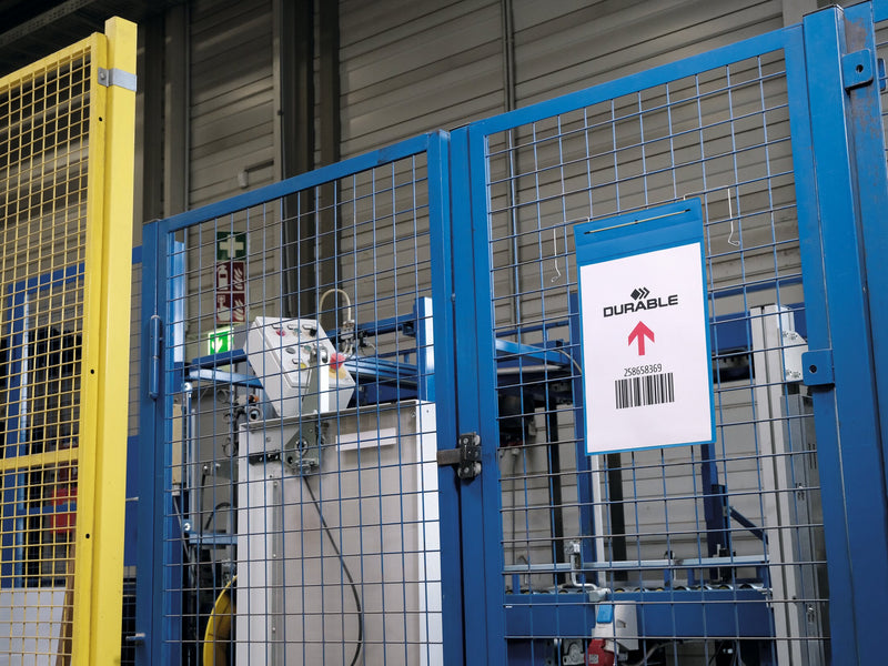 Durable A4 portrait wire hanger pocket on a mesh partition beside warehouse machinery