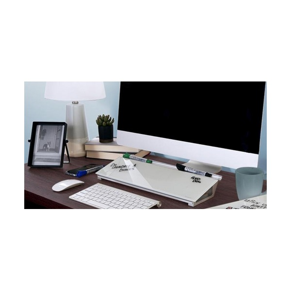 Home office desk with the glass computer pad between a monitor and a white keyboard, markers on its top ledge and handwritten notes on the glass