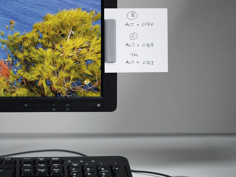 Silver Durafix clip on the edge of a computer monitor holding a handwritten note