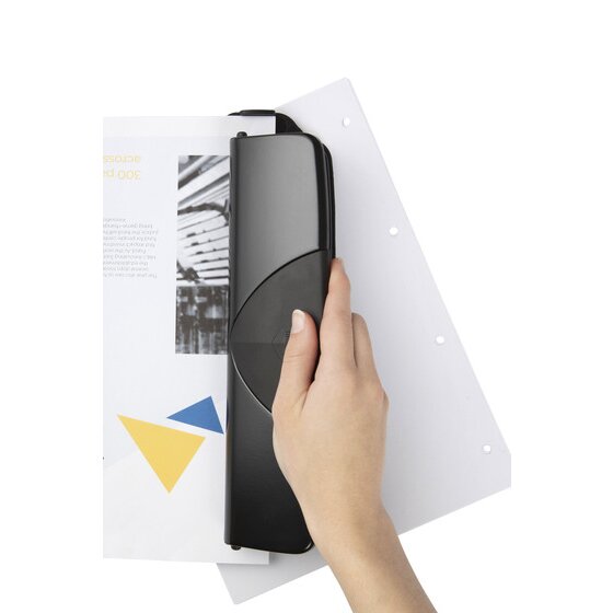 Hand pressing a black four hole punch against a sheet of paper, with four punched holes visible along the edge