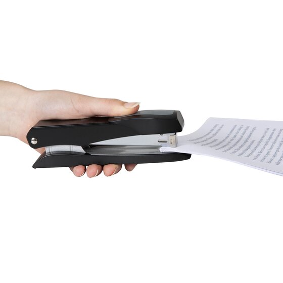 A hand holding a black Marbig full strip metal stapler against a sheet of paper