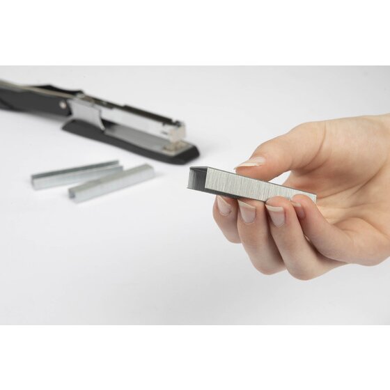 A hand holding a strip of heavy duty staples in front of an open black heavy duty stapler and two loose staple strips