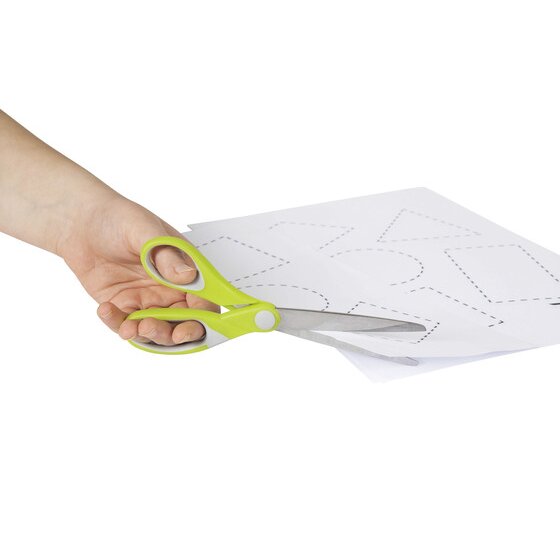 A hand holding a lime and grey Comfort Grip pair while cutting white paper printed with dashed shapes, the ACCO in use photograph for code 975421