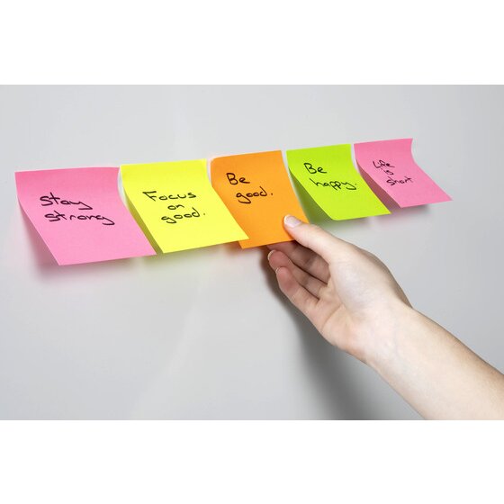 Hand placing a row of five handwritten notes in pink, yellow, orange, green and pink onto a pale grey wall