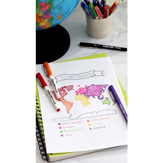 Artline 210 pens colouring a hand drawn continents map in a notebook beside a globe, with an Artline 220 pen nearby