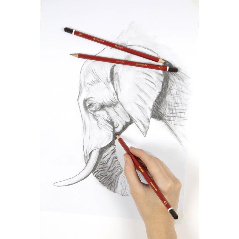 A hand sketching an elephant's head in pencil on white paper, with two red Columbia Copperplate pencils with dark brown caps lying across the upper part of the drawing