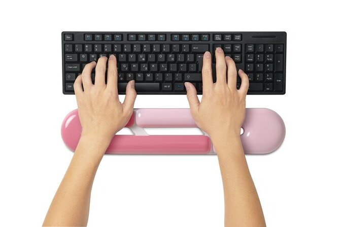 Person using a black keyboard with a pink wrist rest on a white background