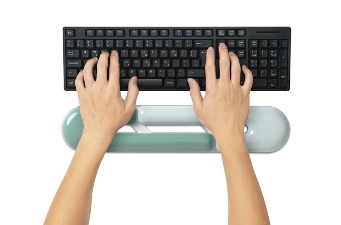 Person using a keyboard with wrist support on a white background