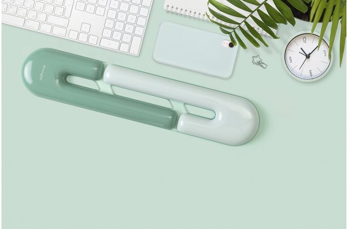 Desk organizer with a keyboard on a light green surface, featuring a clock and plant.