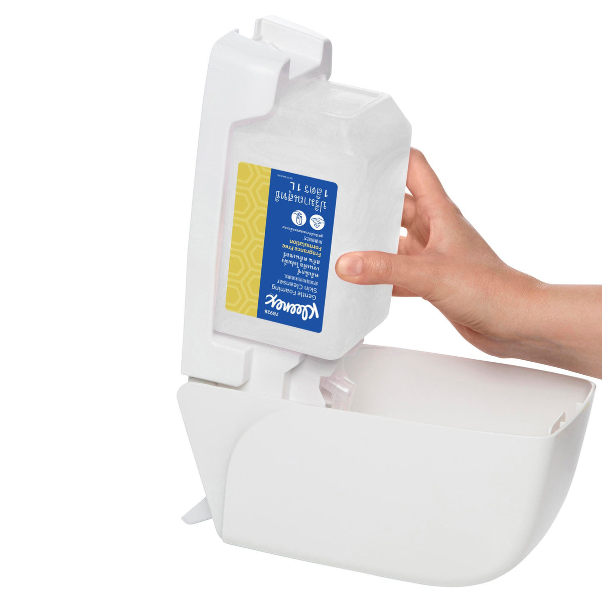 Hand loading a Kleenex Gentle Foaming Skin Cleanser cartridge upside down into an open white wall dispenser, showing how the sealed refill sits in the dispenser housing
