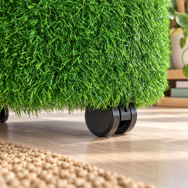 Close up view of the MTA Essentials Aalto Grass Ottoman highlighting the dense green artificial grass texture and a black castor beneath the upholstered base. The detailed image demonstrates the tactile surface and mobile construction, with the ottoman positioned on a timber floor in a warm indoor learning environment.
