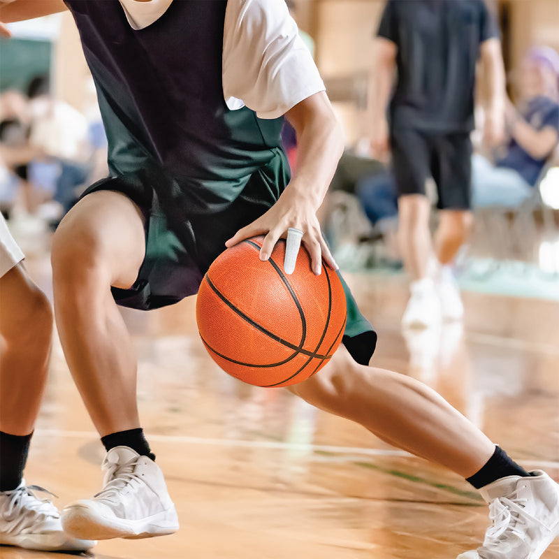 Basketball player controlling a ball while wearing a tubular finger bandage, showing how flexible finger support can be used during suitable sporting and active environments.