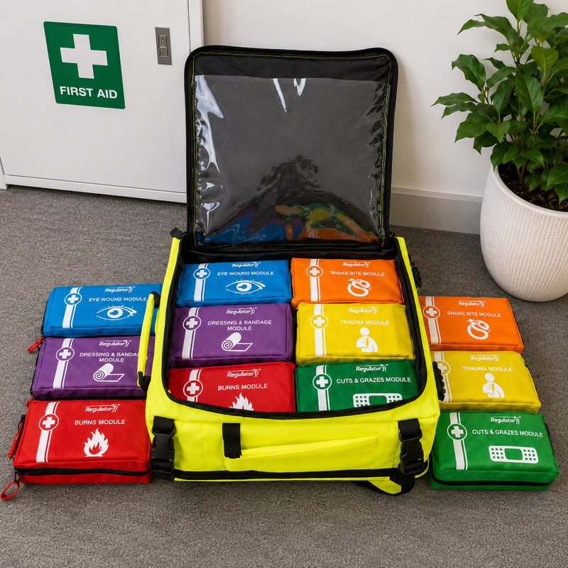 Open AeroKit Modulator Guardian backpack displayed in a workplace first aid area with colour coded eye wound, dressing, burns, snake bite, trauma, and cuts and grazes modules arranged for easy identification.