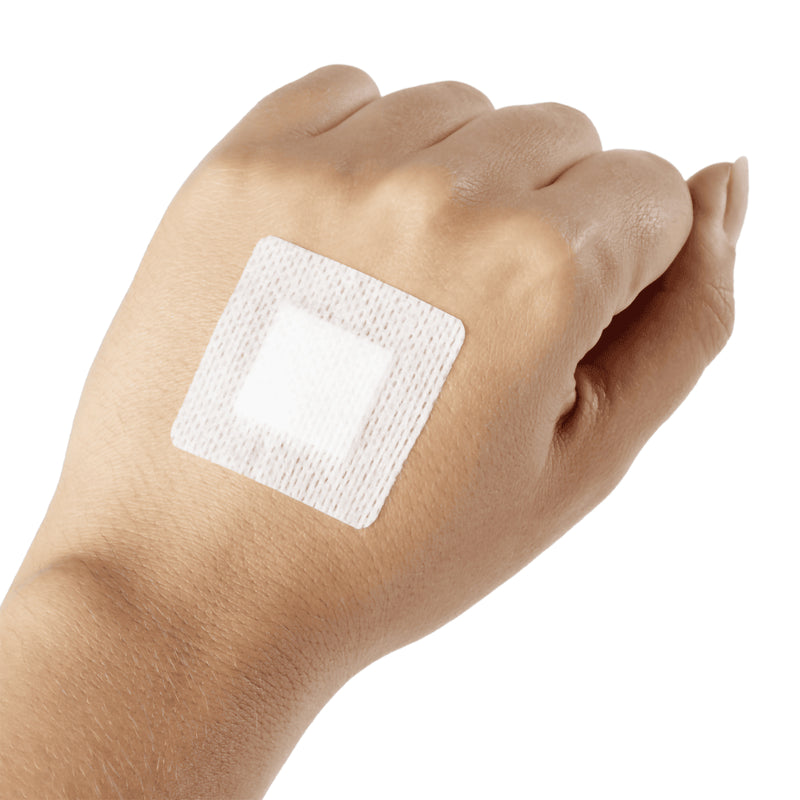 AeroPlast Sensitive Silicone small square wound patch positioned on the back of a hand against a plain white background.