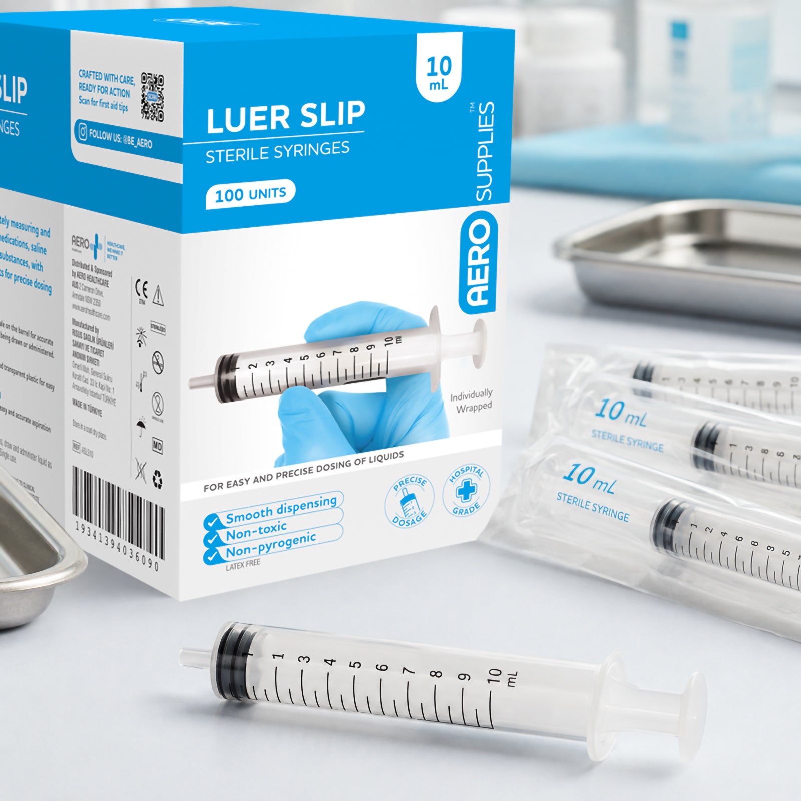 AeroSupplies 10ml Luer Slip Syringe box displayed in a clinical setting with individually wrapped syringes and an unpackaged syringe nearby. The packaging identifies the 10ml capacity, box quantity of 100 units and sterile syringe format for precise dosing of compatible liquids.