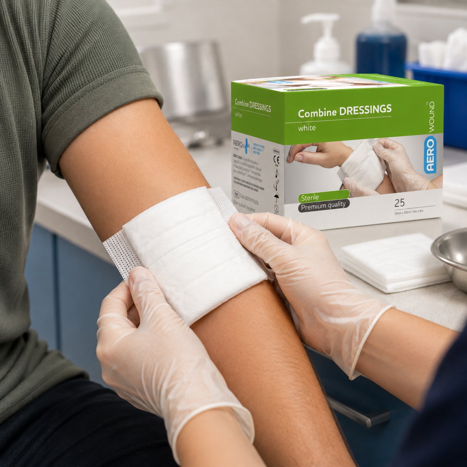 Healthcare professional wearing disposable gloves applies an AeroWound Combine Dressing to a patients upper arm in a clinical treatment setting, demonstrating the soft white dressing positioned over the wound area. An AeroWound Combine Dressings box is visible behind the patient, highlighting the sterile 10 x 10cm dressing format supplied in a box of 25.