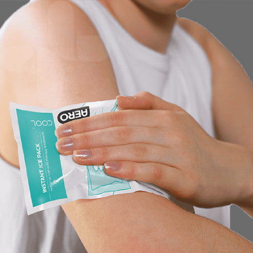 A person holding an AEROCOOL instant ice pack against the outside of their upper arm, the printed face of the pouch turned towards the camera