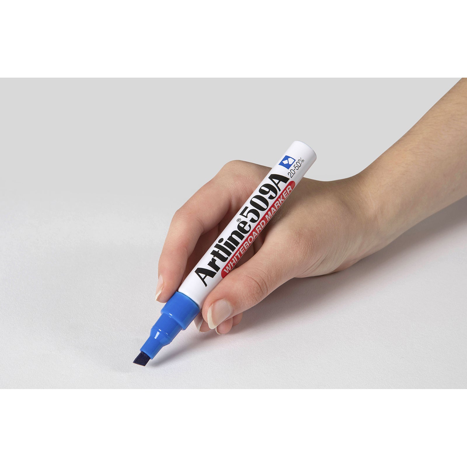 Close up of a hand comfortably holding the Artline 509A Blue Whiteboard Marker against a clean white background. The image clearly displays the ergonomic grip, aluminium barrel and chisel nib, showcasing control and precision during writing.